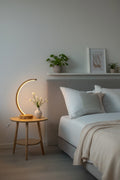 Arc wood LED table lamp with touch dimmer on bedside table