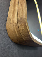 Close-up of a curved wooden frame with visible grain and scratches, resting against a dark gray textured surface.