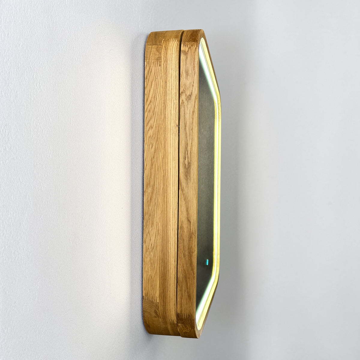A modern wall-mounted light fixture with a rectangular wood-grain frame and a glowing LED border, shown mounted on a white textured wall.