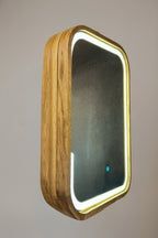 A rectangular wall mirror with rounded corners, featuring a natural wood grain frame and a glowing white LED light border, shown against a neutral gray background.