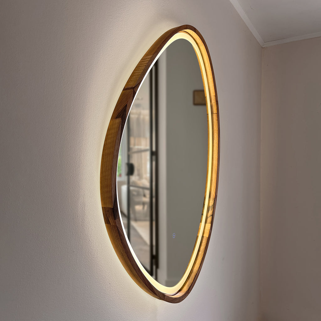 Asymmetrical teardrop wood wall mirror with warm LED light in a walnut frame