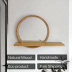 A natural wood wall mirror with a circular frame and a matching horizontal shelf, mounted on a white wall. Four dark gray text badges at the bottom read 'Natural Wood', 'Handmade', 'Eco product', and 'Free Shipping'.