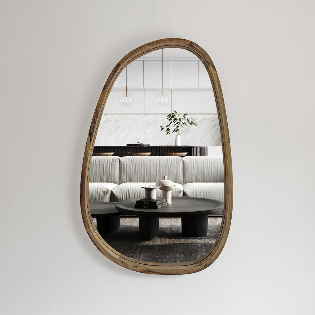 Organic-shaped wall mirror reflecting a sofa and coffee table