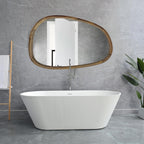 Asymmetric wooden mirror above a freestanding bathtub in a marble bathroom