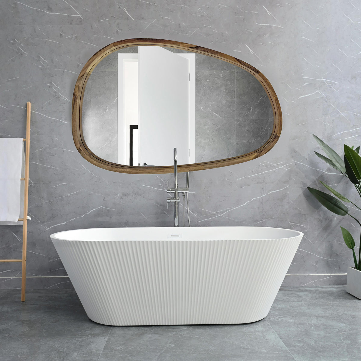 Asymmetric wooden mirror above a freestanding bathtub in a marble bathroom