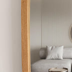 A modern interior scene with a light gray sofa, a white pillow, a ribbed beige wall, and a vertical light wood panel in the foreground.