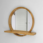 Round wood mirror with shelf on a white wall