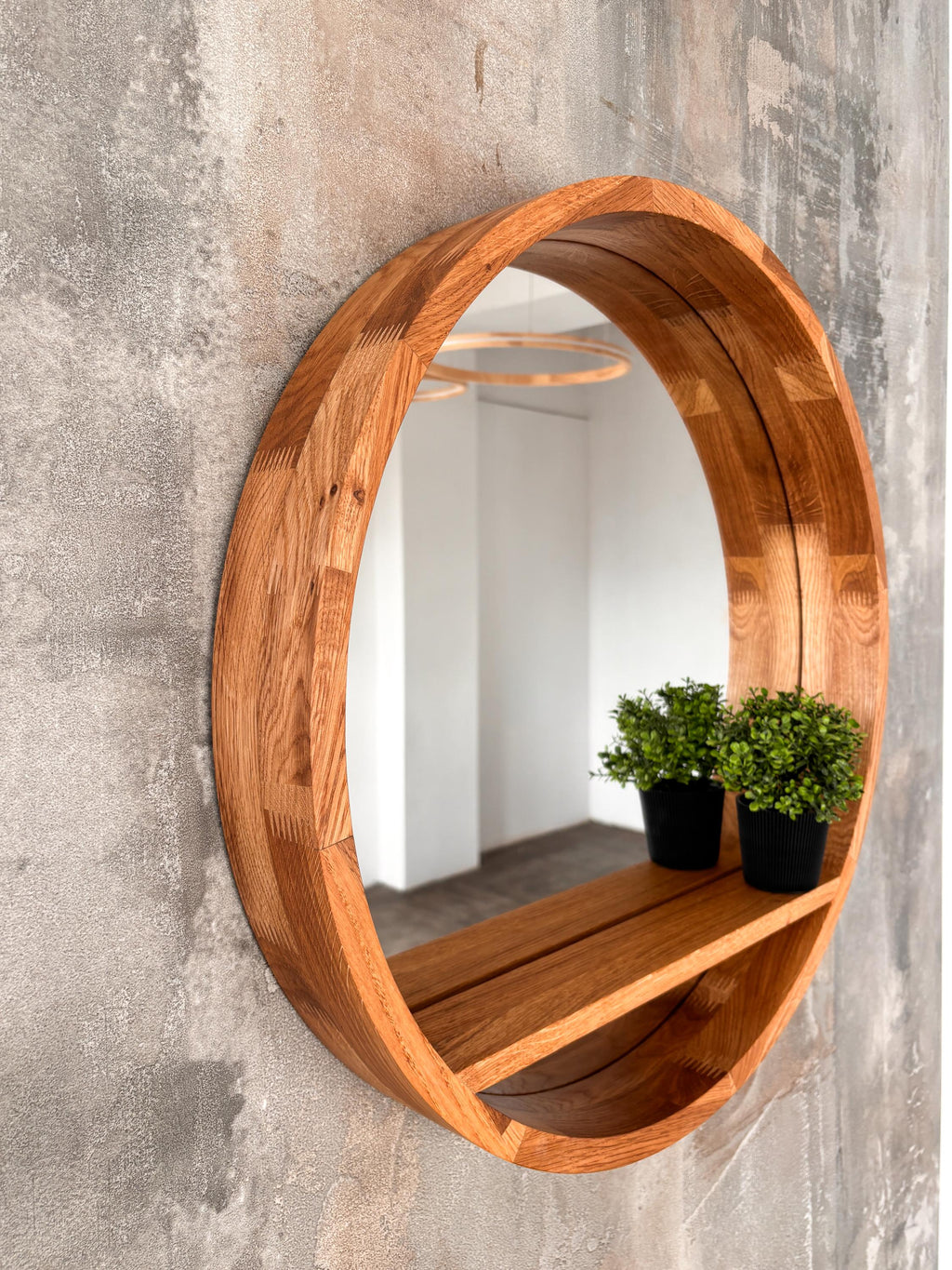 Angled view of the round mirror and its integrated floating shelf