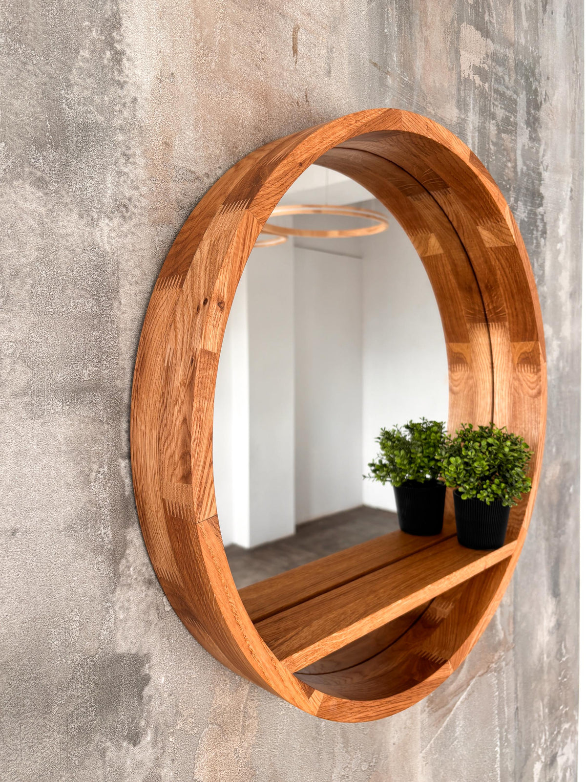 Angled view of the round mirror and its integrated floating shelf