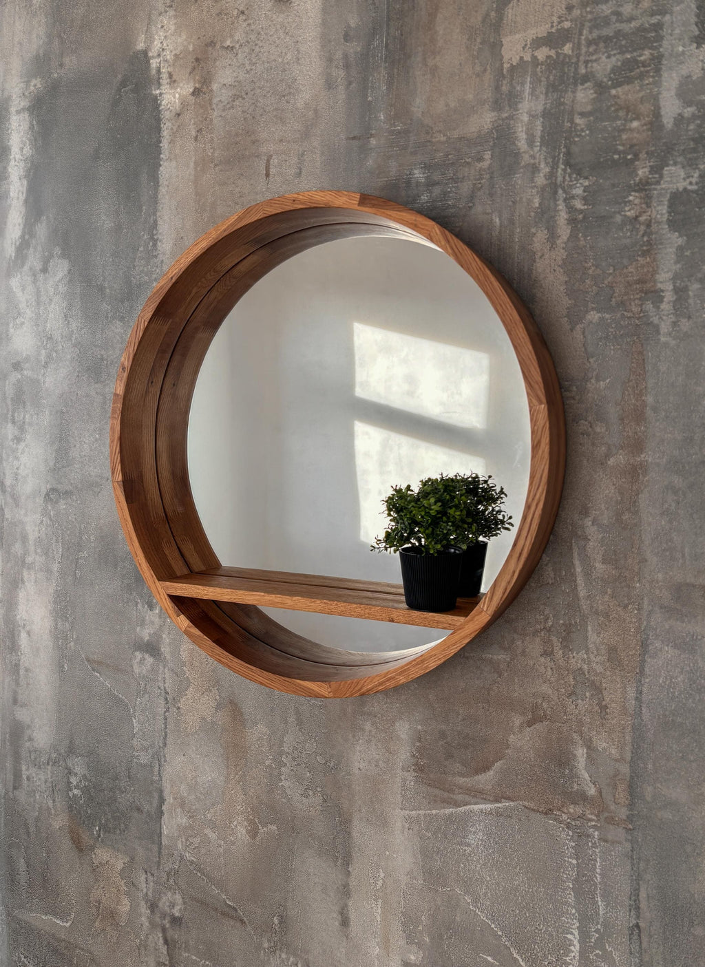 Round mirror with shelf styled with a small plant