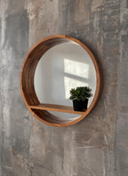 Round mirror with shelf styled with a small plant