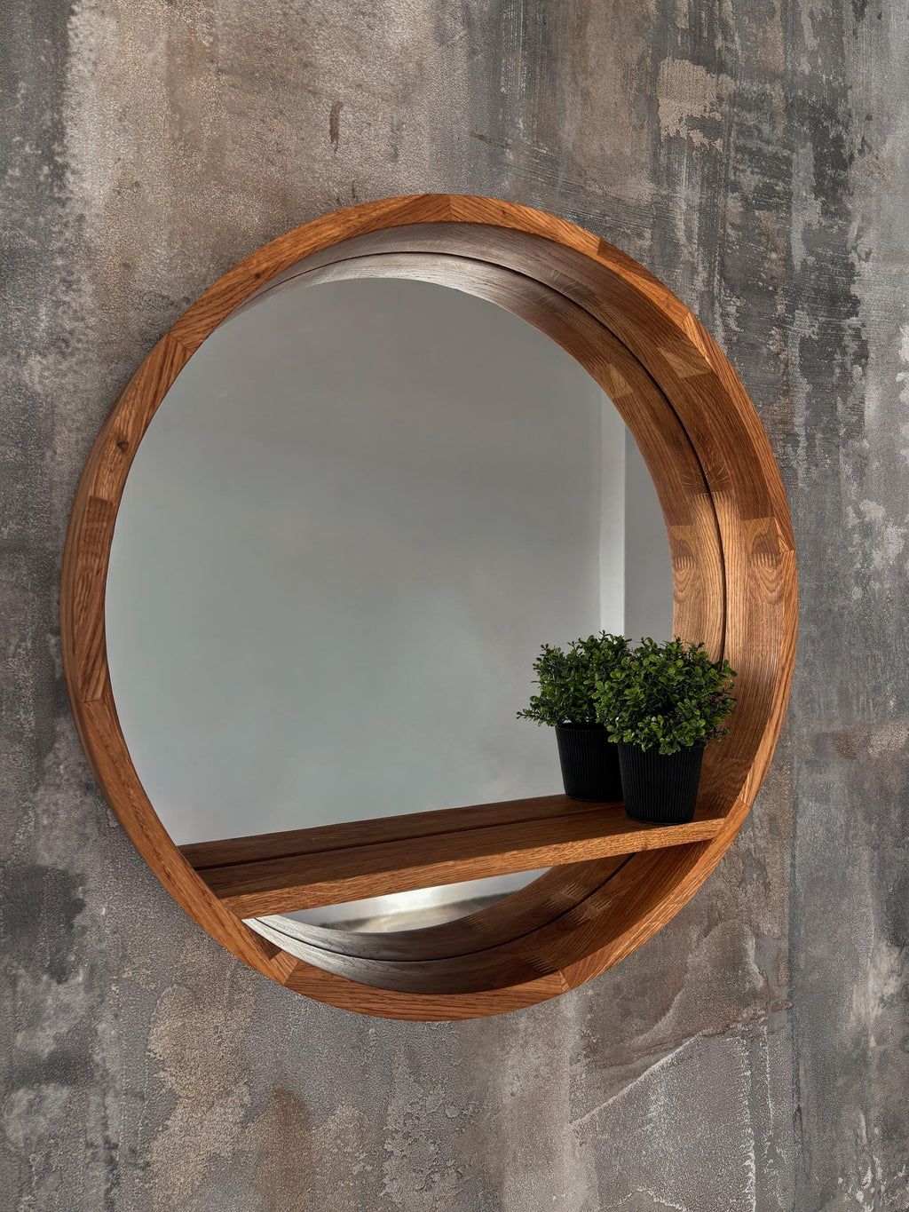 Round wood mirror with shelf on a concrete wall