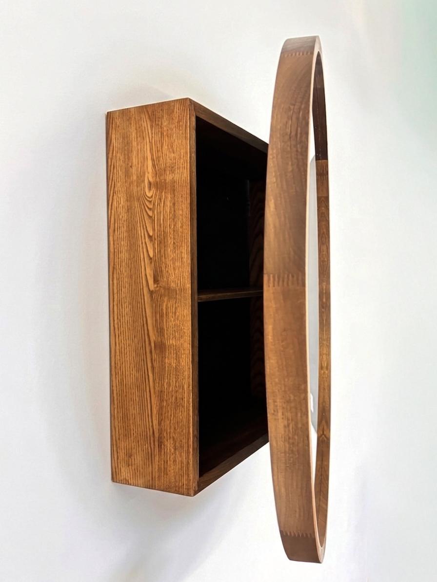 Round mirror cabinet with the mirrored door open, showing hidden storage