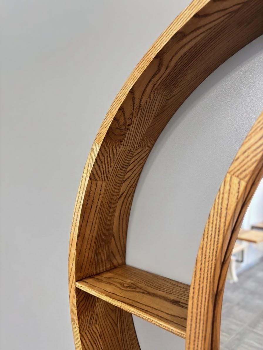 Profile of the round mirror frame against a light wall